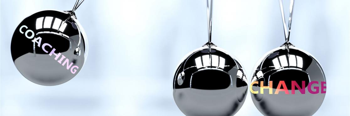 Silberne Pendelkugeln mit den Wörtern 'Coaching' und 'Change' symbolisieren Impulse für Veränderung durch professionelles Executive Coaching